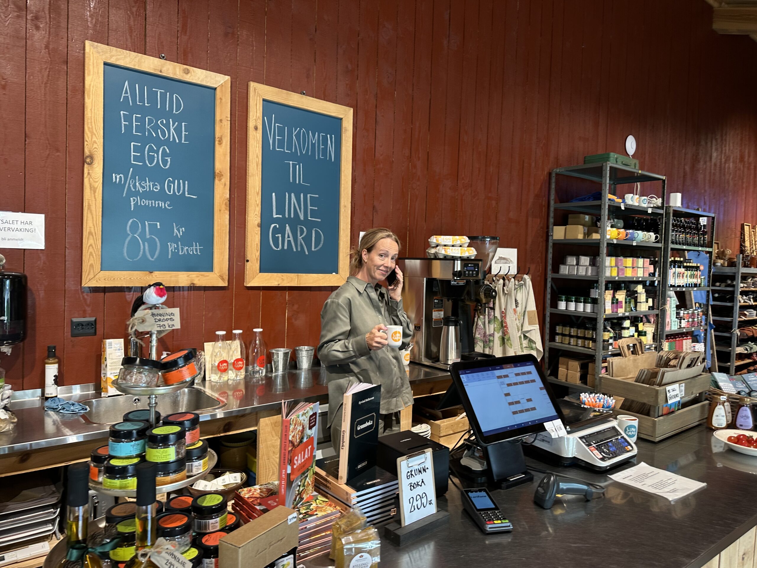 Gårdsutsalg på Jæren. Line gard, med Heidi Line bak disken med telefon i hånda og kaffekopp i hånda.
